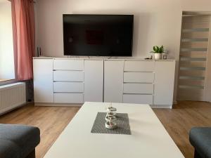 een woonkamer met een wit entertainmentcentrum met een tv bij Apartament Zofia in Duszniki Zdrój