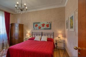 una camera da letto con un letto con una coperta rossa e un lampadario a braccio di Locanda Villa Moderna a Genova