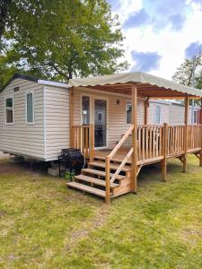 une petite maison avec une terrasse couverte et un kiosque dans l'établissement Mobil home camping 4 étoiles les Viviers 2 chambres, à Lège-Cap-Ferret