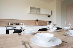 a kitchen with a wooden table with plates and wine glasses at Apartmán v LakeParku in Staré Splavy