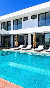 a swimming pool with lounge chairs in front of a building at Luxury House Buena vista in Ica