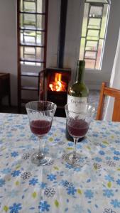 dois copos de vinho sentados numa mesa com uma garrafa de vinho em Chalé doce beija-flor em Campos de Jordão