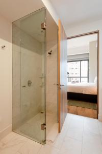 a glass shower in a bathroom with a bedroom at Londres 256 by Wynwood House in Mexico City
