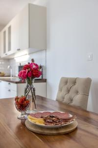einen Tisch mit einem Teller Essen und Blumen darauf in der Unterkunft Apartment Vigo in Kaštela