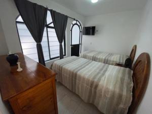 1 dormitorio con 2 camas y tocador de madera en Casa Tenorio Hospedaje en Orizaba