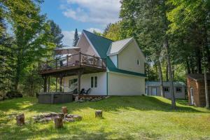 a large white house with a deck on a yard at Eastern Township's Getaway! Beach + Ski Haven in Magog-Orford
