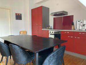 eine Küche mit roten Schränken sowie einem schwarzen Tisch und Stühlen in der Unterkunft MannheimMitte Zimmer3 Denkmalschutz Stadthaus - 2 Personen in Mannheim