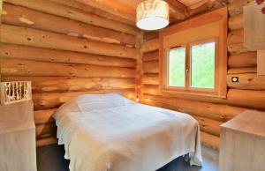 a bedroom with a bed in a log cabin at L'Etoile du Berger in Saint-Martin-de-la-Porte