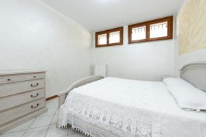 - une chambre avec un lit, une commode et 2 fenêtres dans l'établissement Manerba CENTRO GardaSee e parcheggio, à Manerba del Garda