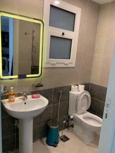 a bathroom with a sink and a toilet and a mirror at Lovely Cosy 1 Bedroom in Stella Sidi Abdelrahman families only in El Alamein