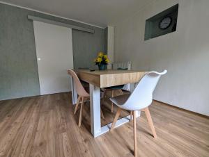 a dining room table with two chairs and a clock on the wall at L'Échappée Verte in Betting-lès-Saint-Avold +3 photos