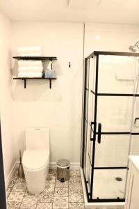 a bathroom with a toilet and a glass shower at Hibiscus House in Stratford