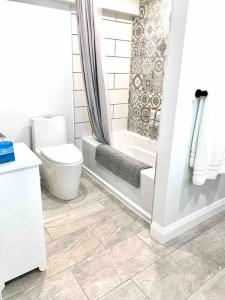 uma casa de banho branca com um WC e um chuveiro em Hibiscus House em Stratford