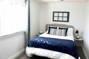 a bedroom with a blue and white bed with a window at Hibiscus House in Stratford