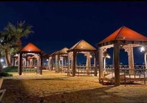 una fila di padiglioni sulla spiaggia di notte di شاليه 3 غرف قريه بلومار الدوم عائلات للإقامة يطلب موافقه امنيه قبل 48 ساعه من الاقامه - توجد مصاريف لبوابة القرية - استهلاك الكهرباء على العميل a Ain Sokhna