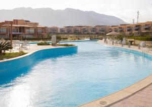 una piscina con acqua blu in un resort di شاليه 3 غرف قريه بلومار الدوم عائلات للإقامة يطلب موافقه امنيه قبل 48 ساعه من الاقامه - توجد مصاريف لبوابة القرية - استهلاك الكهرباء على العميل a Ain Sokhna
