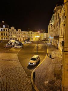 un grupo de autos estacionados en un estacionamiento por la noche en Podkrovní byt na Velkém náměstí s Wi-Fi zdarma en Hradec Králové