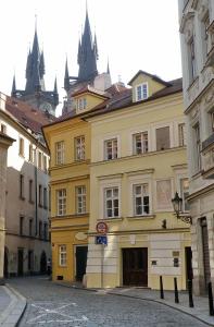 un bâtiment jaune dans une rue à côté de certains bâtiments dans l'établissement Residence Týnská, à Prague