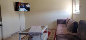 ein Wohnzimmer mit einem Sofa und einem TV an der Wand in der Unterkunft appartement meublé avec wifi in Safi