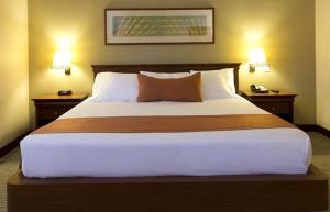 a large bed in a hotel room with two night stands at Lagos Suítes in Guapé