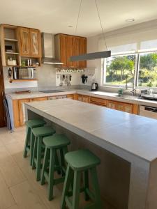 a kitchen with a large counter with four green bar stools at Ventarrón Pueblomio Manantiales in Manantiales