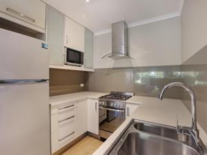 uma cozinha com armários brancos e um lavatório de aço inoxidável em Eagle Heights Holiday Units em Eden