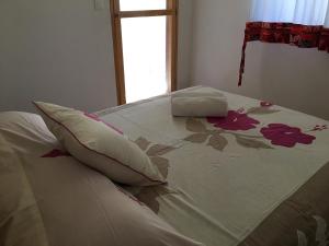 a white bed with flowers on it with a window at Pension Te Aroha - Te Rai in Maatea
