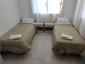 2 camas en una habitación pequeña con ventana en Duplex Escritores Argentinos en Rawson