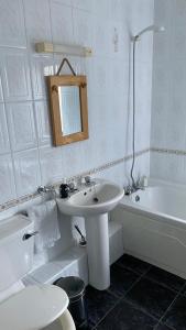 y baño blanco con lavabo y bañera. en Hill Sea View Cottage en Glengarriff