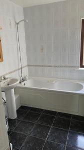 a bathroom with a white tub and a sink at Hill Sea View Cottage in Glengarriff