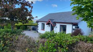 a small white house with a yard at Hill Sea View Cottage in Glengarriff