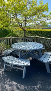 a picnic table and benches next to a wooden fence at Hill Sea View Cottage in Glengarriff
