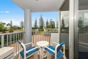 Balcón con 2 sillas, mesa y mesa en Sandpiper Broadbeach en Gold Coast