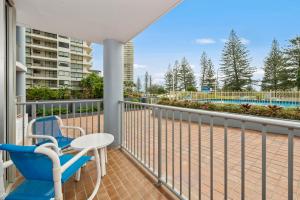 a balcony with a table and chairs and a view of a pool at Sandpiper Broadbeach in Gold Coast