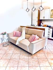 a white couch in a living room with pink pillows at Eleonora Home in Porto Torres