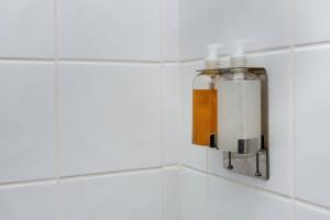 zwei Glasflaschen auf einer gefliesten Wand im Bad in der Unterkunft Croft Road Apartments in Neath