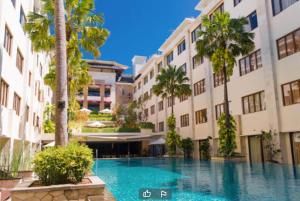 uma piscina no meio de um edifício com palmeiras em Stylish 2 Bedroom Penthouse Apt, 50 Mbps, Pool, Gym, Resto em Kuta