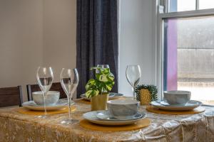 a table with wine glasses and plates on it at Croft Road Apartments in Neath