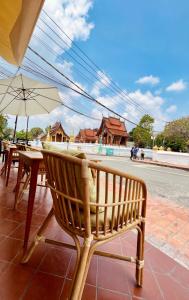 um banco de madeira com uma mesa e um guarda-chuva em Barn Laos Luangprabang Hostel em Luang Prabang