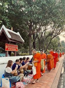 Barn Laos Luangprabang Hostel في لوانغ برابانغ: مجموعة من الرهبان في أردية حمام برتقال يقفون في طابور