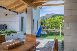 a patio with a wooden table and a playground at Villa Modriola with heated pool in Donji Proložac - Imotski in Donji Proložac +41 photos