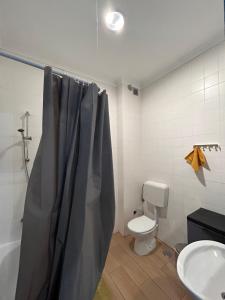 a bathroom with a shower curtain and a toilet at Hostel Sun River in Almada