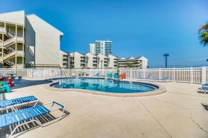 einem Pool mit Stühlen vor einem Gebäude in der Unterkunft Baywatch F5 in Pensacola Beach