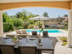 een patio met een tafel en stoelen en een zwembad bij Loustalet Plus in Bagnols-en-Forêt