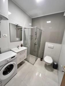een witte badkamer met een douche en een wasmachine bij Apartments by the sea Metajna, Pag - 6465 in Metajna