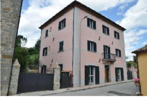 un grand bâtiment rose avec une clôture noire dans l'établissement La Casa del Falegname, à Umbertide