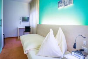 Habitación de hotel con cama con almohadas blancas en Hotel Unione en Bellinzona