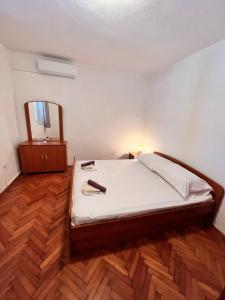 a bedroom with a bed and a mirror on a wooden floor at Apartment Metajna 6465c in Metajna
