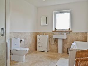 a bathroom with a toilet and a sink and a window at Macneils Croft in Gortenfern