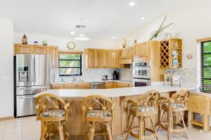 a kitchen with wooden cabinets and a bar with stools at Sombrero Beach Retreat in Marathon